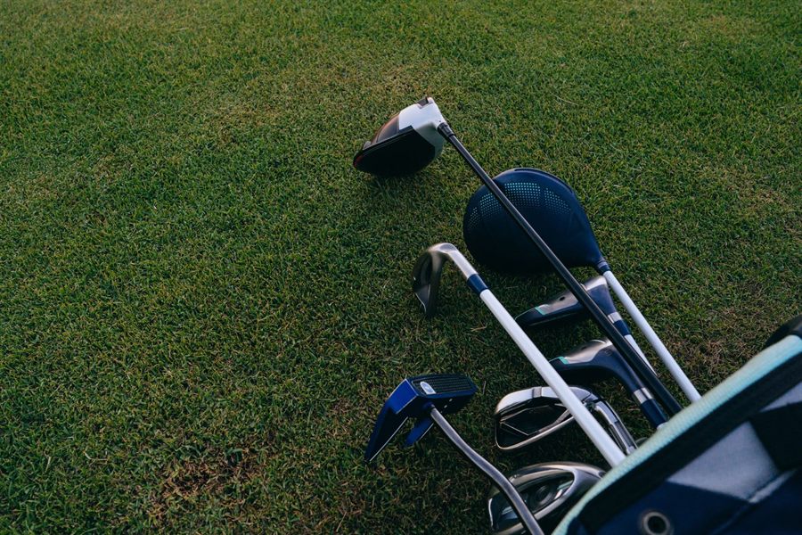 Set of golf irons and a driver on a green lawn, the kind of set found in Hawaii golf club rentals