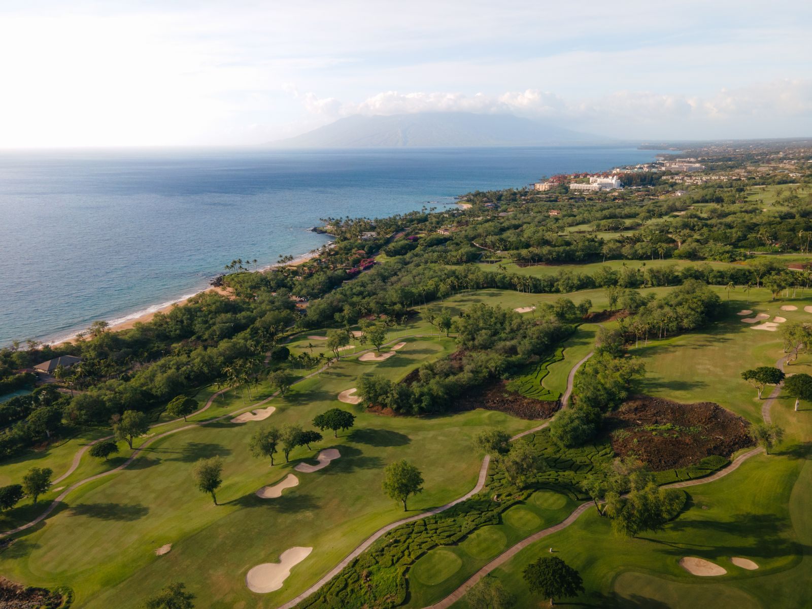 Aerial view of golf in Hawaii, Maui: green fairways and bunkers above the Wailea-Makena coastline